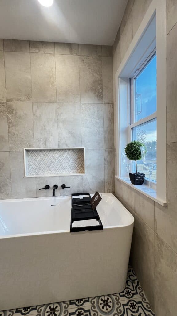 Elegant bathtub with a window view and stylish wall decor in a contemporary bathroom.