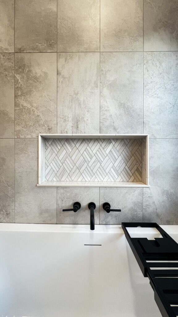 Stylish bathroom wall with large neutral tiles and a decorative niche for toiletries.