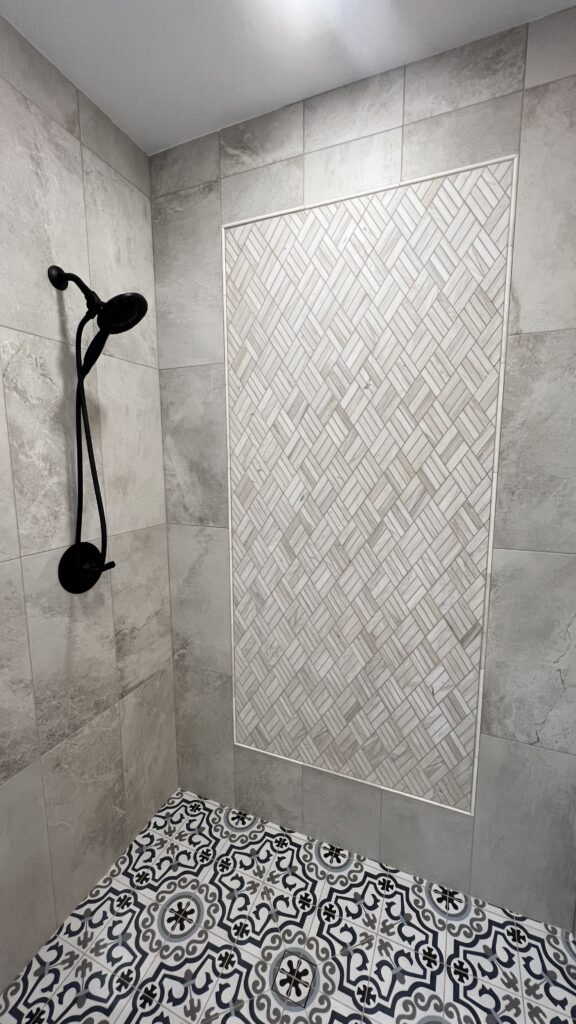 Shower wall with decorative tile accent in a bathroom renovation.