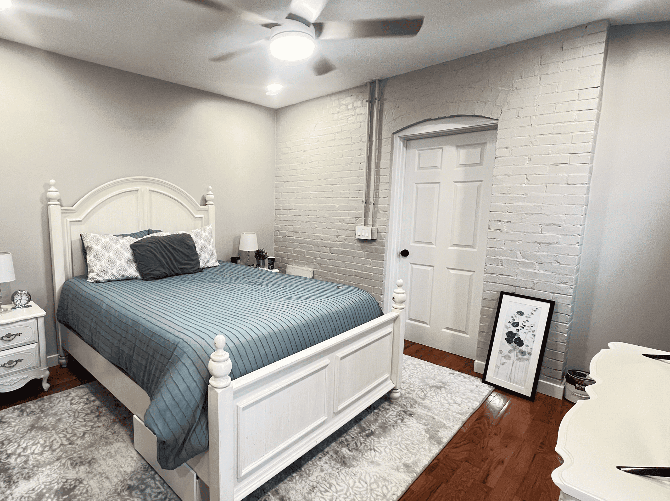 Bright bedroom with white furniture, brick wall, and cozy bedding, perfect for relaxing and resting.