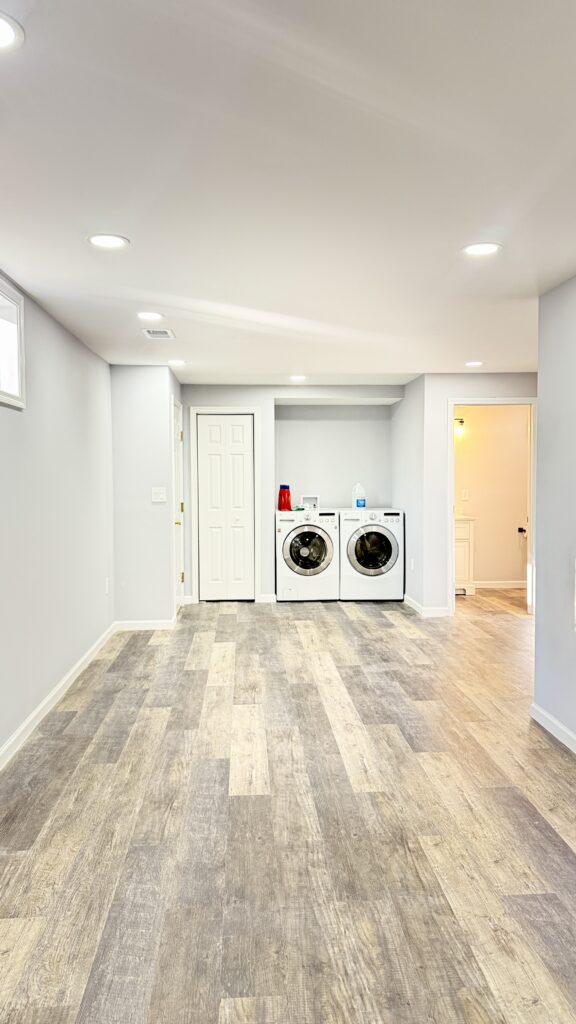 Modern laundry room with washer and dryer in a clean, bright basement space.