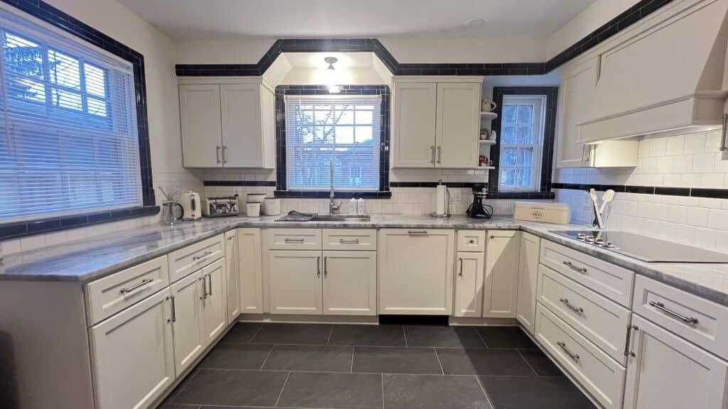Bright and spacious kitchen with white cabinets, black accents, and large windows for natural light.