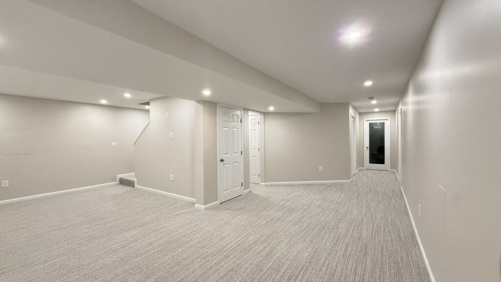 Bright, spacious basement with neutral walls and carpet flooring, ideal for family or entertainment.