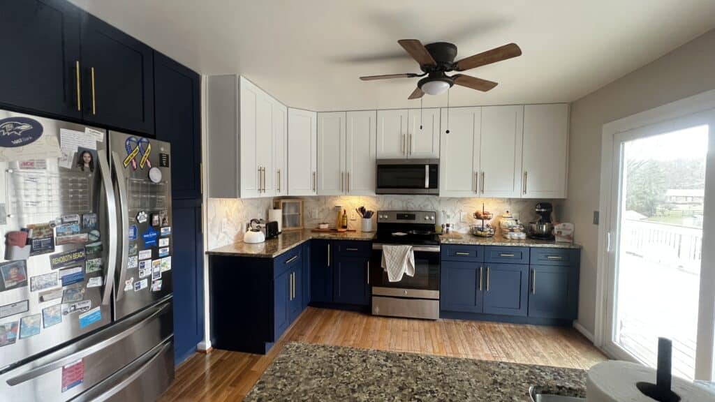 Bright modern kitchen with white and navy cabinets, stainless steel appliances, and natural light.