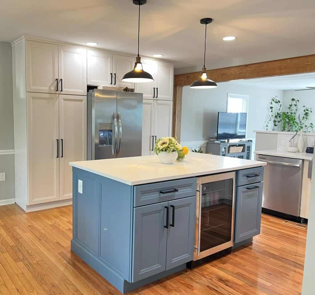 Modern kitchen with blue island and white cabinets.