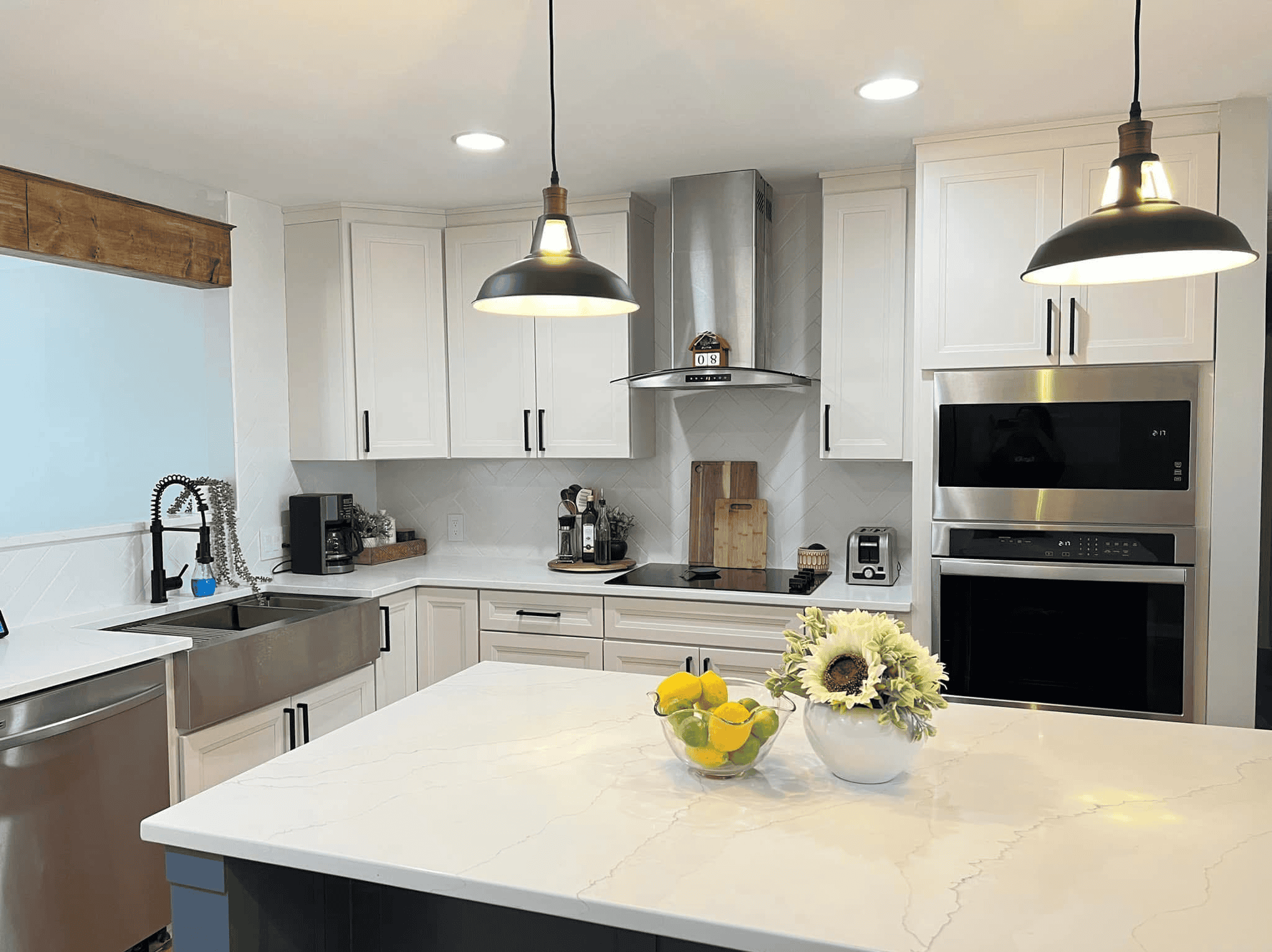 Bright modern kitchen with white cabinets and marble island. Features stainless steel appliances and.