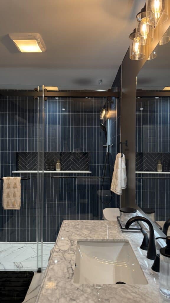 Modern bathroom with blue tiles and marble countertop.