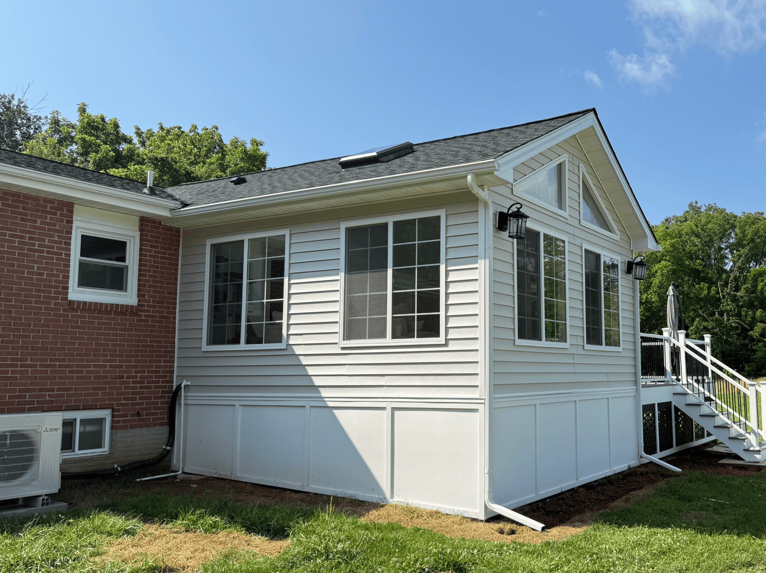 Sunroom addition with large windows and white siding.