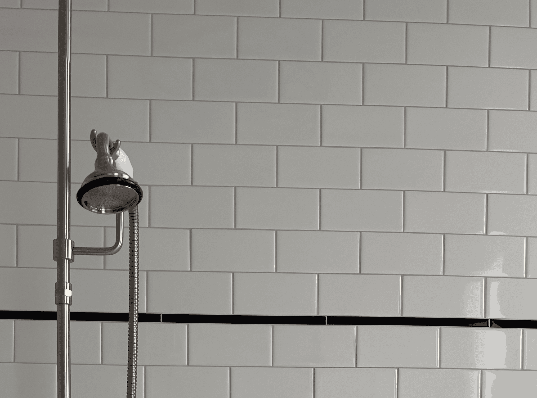 Modern white subway tile shower wall with black accent line.