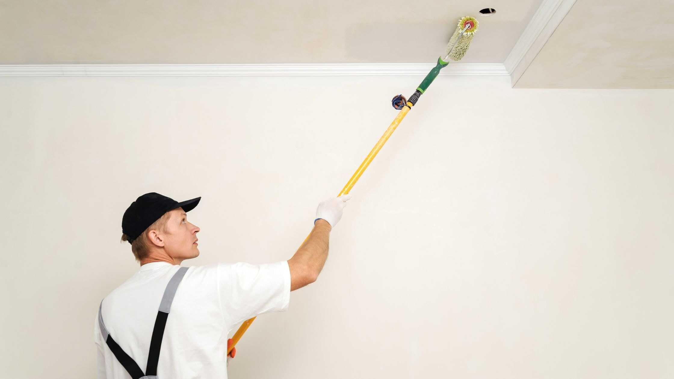 Professional ceiling painting service with a painter using a roller on the ceiling.