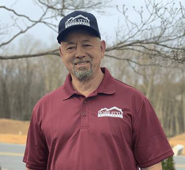 Friendly home improvement professional outdoors, smiling, wearing branded cap and polo shirt.