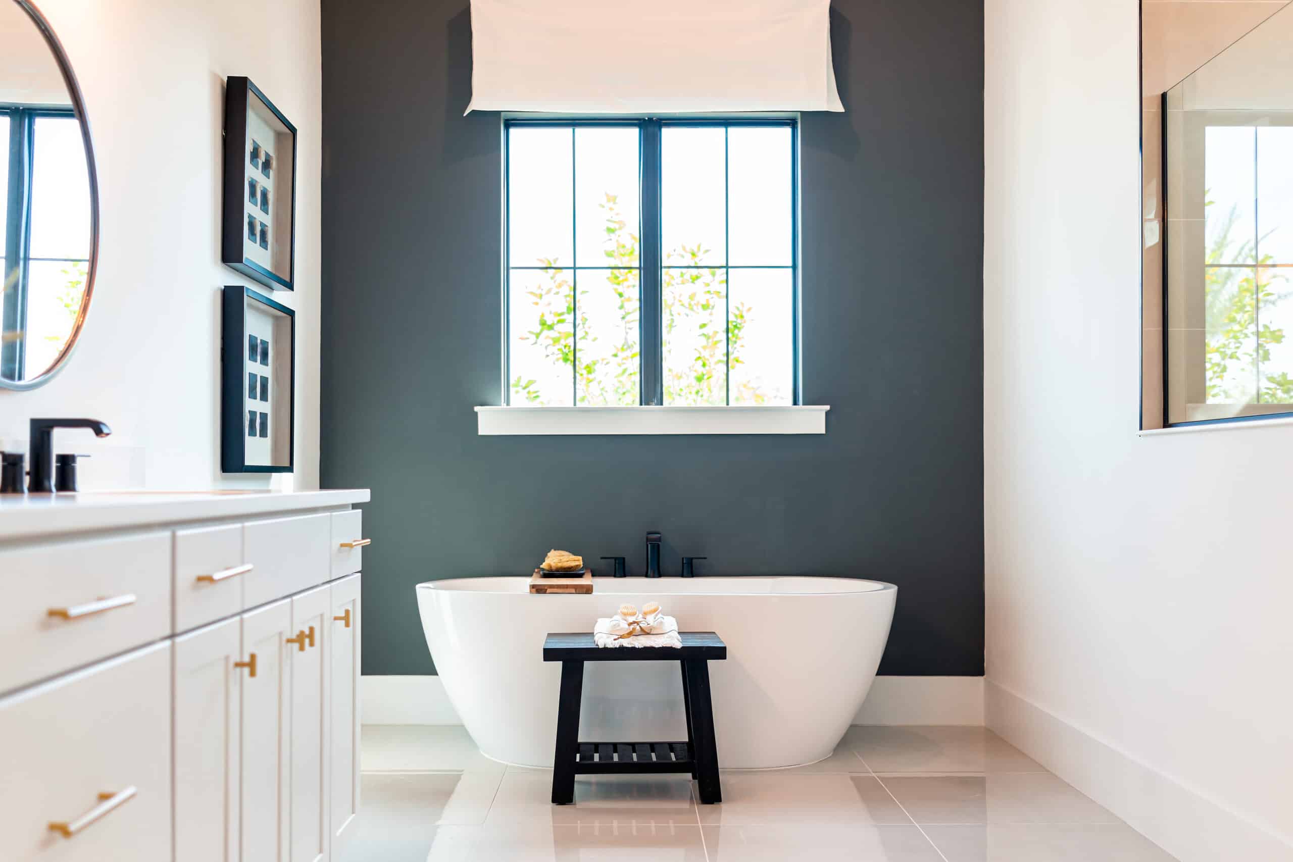 Elegant bathroom with a freestanding bathtub, large window, and stylish decor.